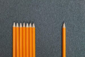 seven orange pencils beside pencil on gray surface