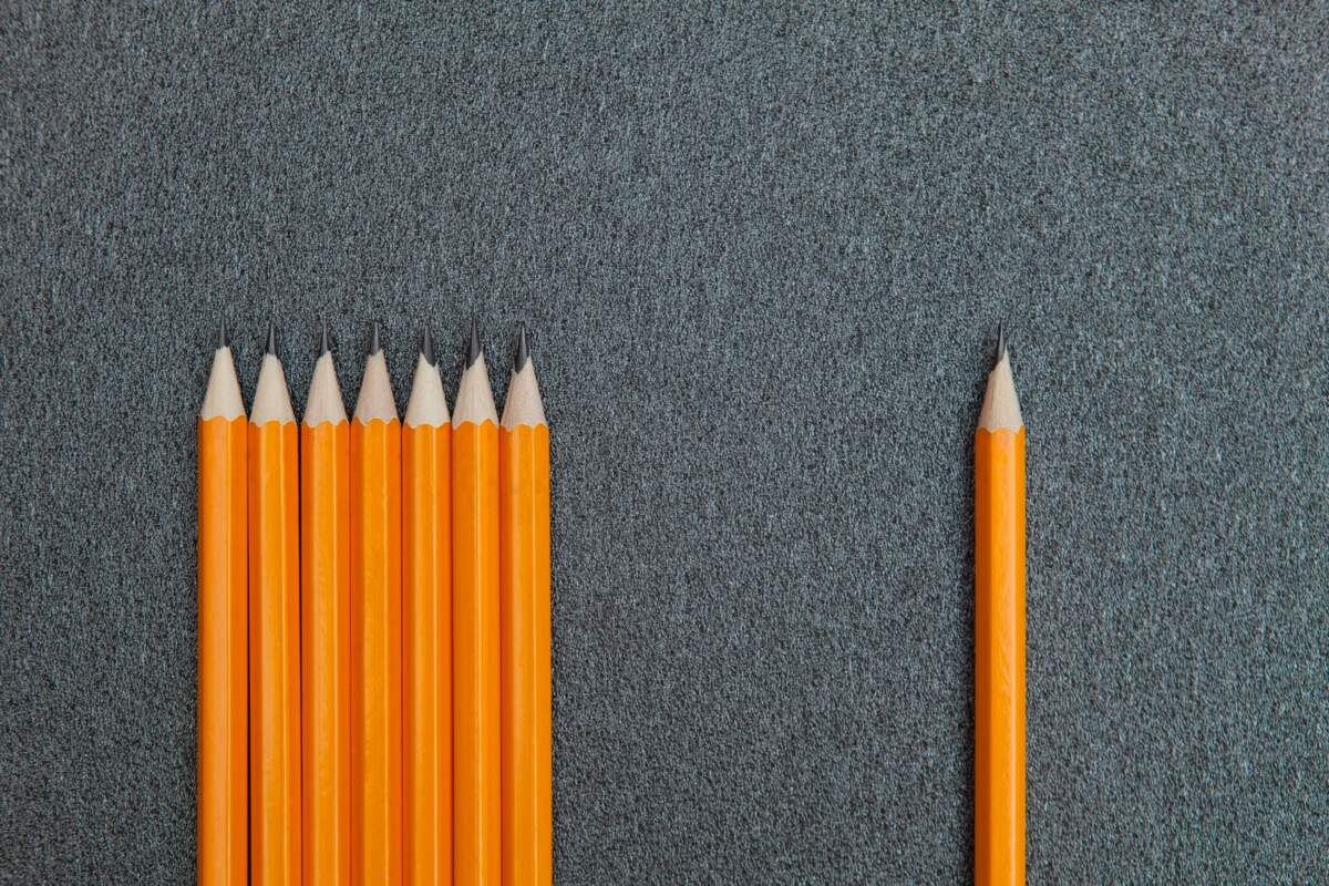 seven orange pencils beside pencil on gray surface